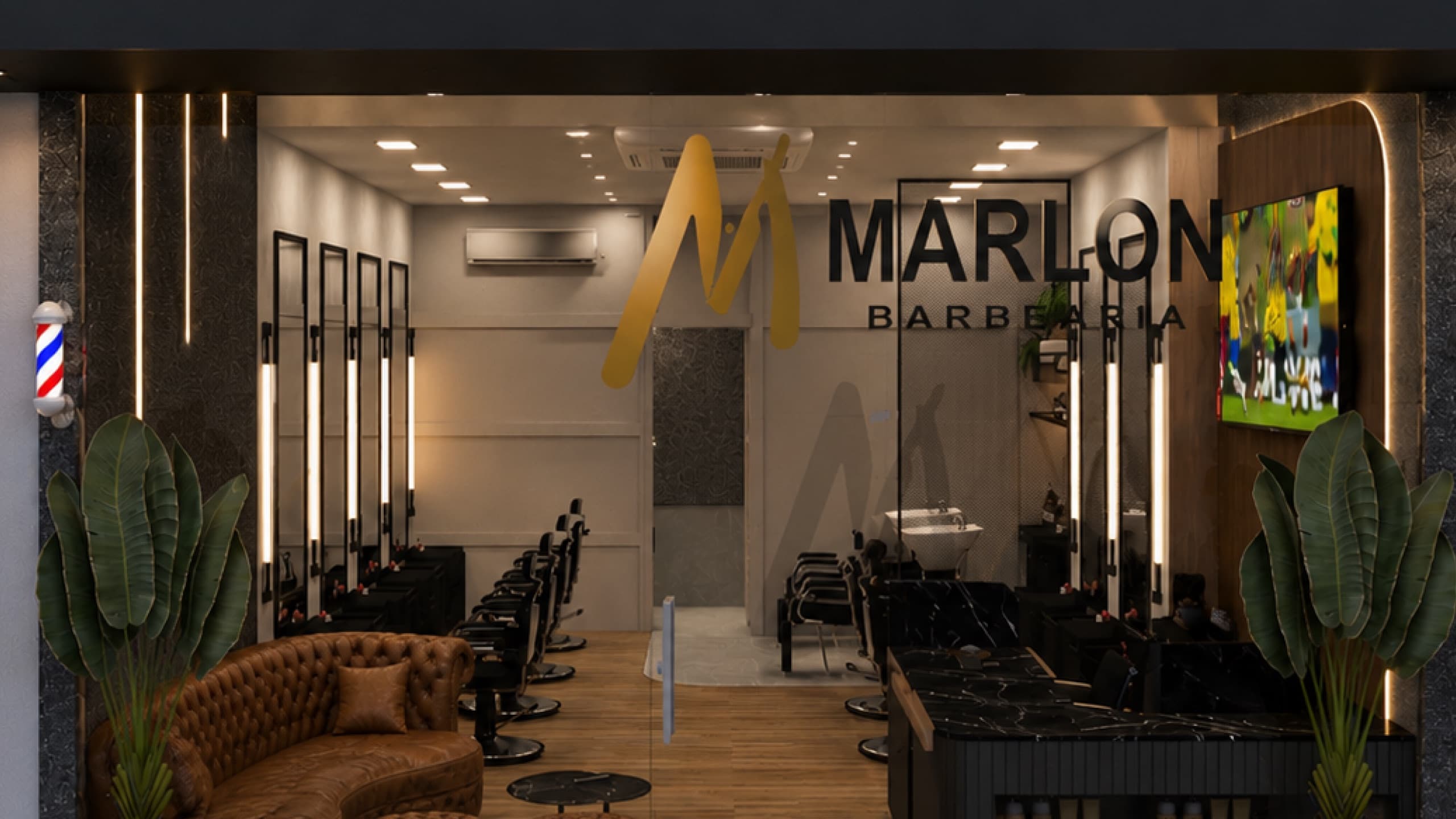 Fachada da Marlon Barbearia com o logo dourado na vitrine, sofá de couro capitonê, cadeiras de barbeiro e espelhos com luz vertical